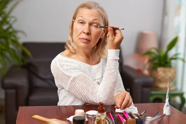 Bonita, mulher idosa aplicando rímel preto, pestanas de tinta usando borla, fazendo, fazendo profissional fazer . — Fotografia de Stock