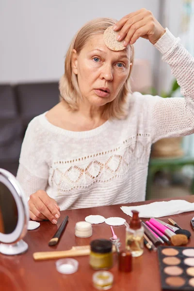 Mulher madura velha saudável rir aplicar creme cosmético hidratante anti envelhecimento no rosto, senhora de meia idade suave cuidados com a pele limpa loção tratamento de beleza natural . — Fotografia de Stock