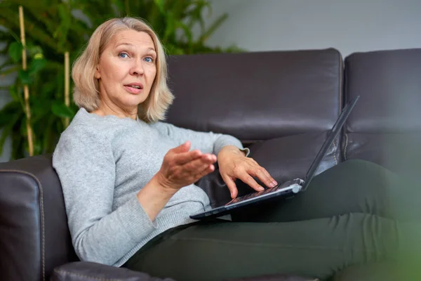 Vrouw liggend op een bank thuis concentreren als ze werkt op een laptop. — Stockfoto