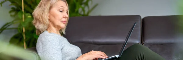 Vrouw liggend op een bank thuis concentreren als ze werkt op een laptop. — Stockfoto