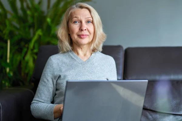 Empresária trabalhando on-line sentado em um sofá em um escritório . — Fotografia de Stock