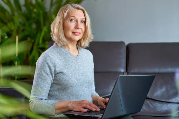 Mulher em um sofá em casa concentrando-se como ela trabalha em um laptop . — Fotografia de Stock
