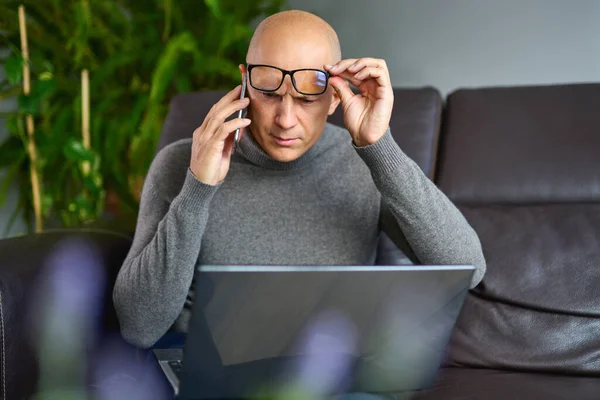 Homem trabalhando em um laptop em branco em um sofá confortável em casa . — Fotografia de Stock