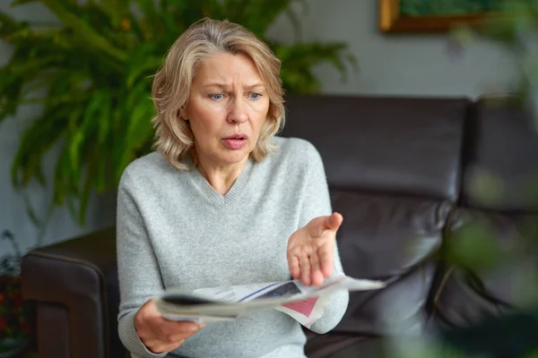 Geschockt, Frau liest Zeitung, schlechte Nachrichten. — Stockfoto