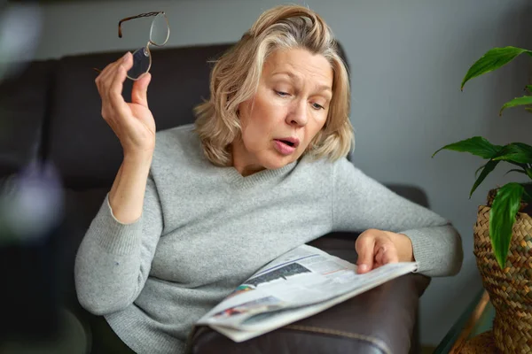 Geschockt, Frau liest Zeitung, schlechte Nachrichten. — Stockfoto