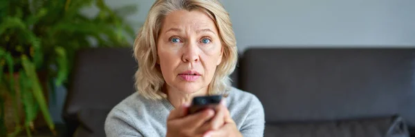 Volwassen vrouw die thuis televisie kijkt. — Stockfoto