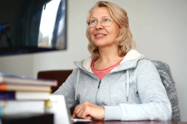 Mujer de mediana edad en gafas utilizando el correo electrónico de escritura portátil que trabaja en la oficina en casa, señora que busca información en Internet o comunicarse en línea — Foto de Stock