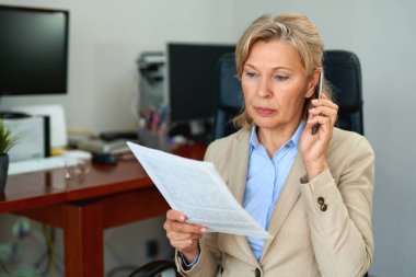 Ofis içi belgelerle çalışan kıdemli iş kadını..