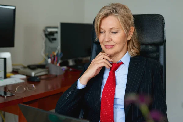 Porträt einer reifen weiblichen Chefin, die im Büro auf einem Stuhl sitzt — Stockfoto