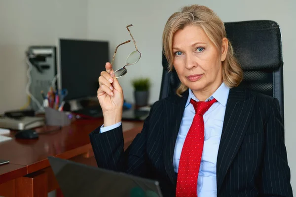 Porträt einer reifen weiblichen Chefin, die im Büro auf einem Stuhl sitzt — Stockfoto