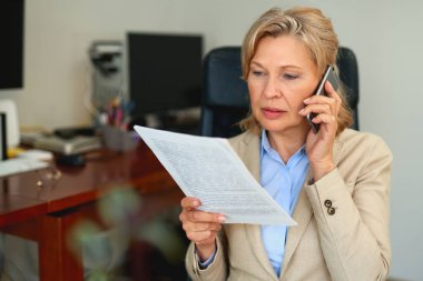 Ofis içi belgelerle çalışan kıdemli iş kadını..