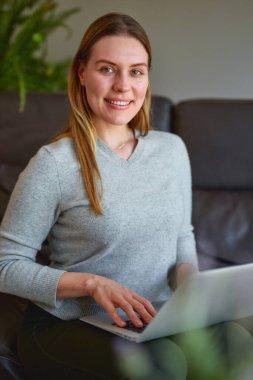 Evde dizüstü bilgisayar kullanan güzel bir kadın.