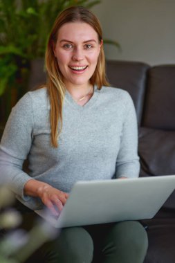 Evde dizüstü bilgisayar kullanan güzel bir kadın.