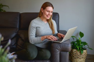 Evde dizüstü bilgisayar kullanan güzel bir kadın.