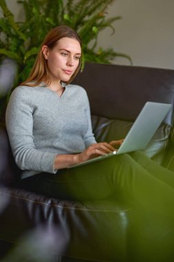 Evde dizüstü bilgisayar kullanan güzel bir kadın.