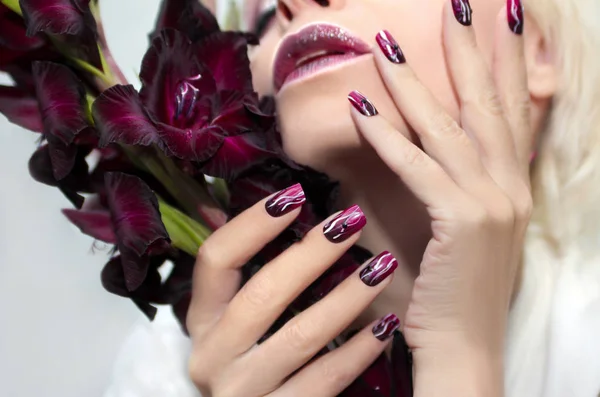 Burgundy manicure with gladiolus. — Stock Photo, Image