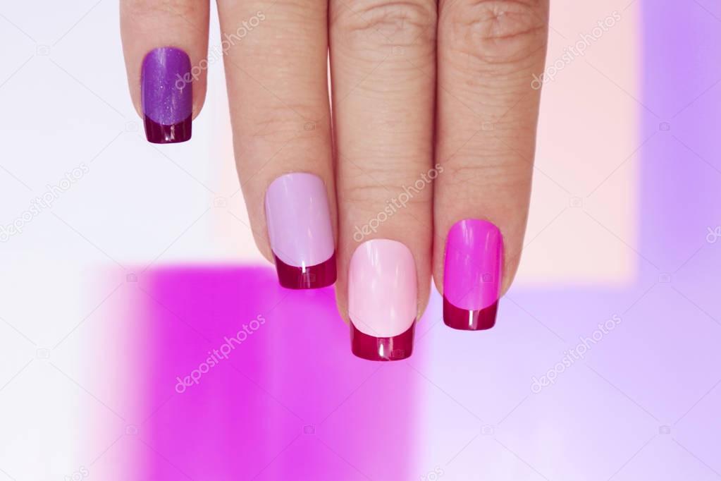 Pink lilac colored French manicure on female hand close up.