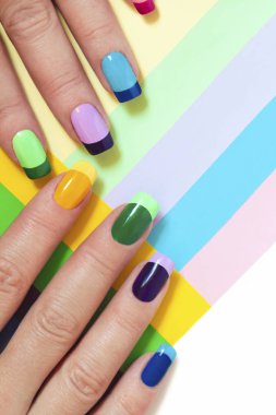 Multi-colored pastel manicure combined tone on tone with a striped background.Nail art. clipart