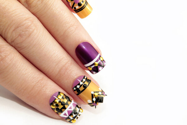 Manicure with colorful ethnic design with rhinestones on female hand close up on white background.