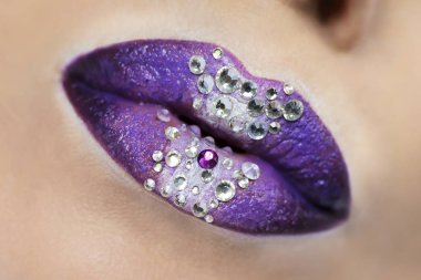 Creative lip design.Makeup with purple and white lipstick with rhinestones in the center.
