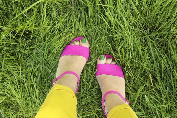 草坪上长着绿色指甲油的粉红凉鞋 背景是青草 — 图库照片