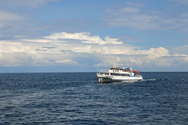 Deniz Burnu. Mavi gökyüzü bulutlu ve sakin deniz. İnsanlar yazın deniz yoluyla seyahat eder..