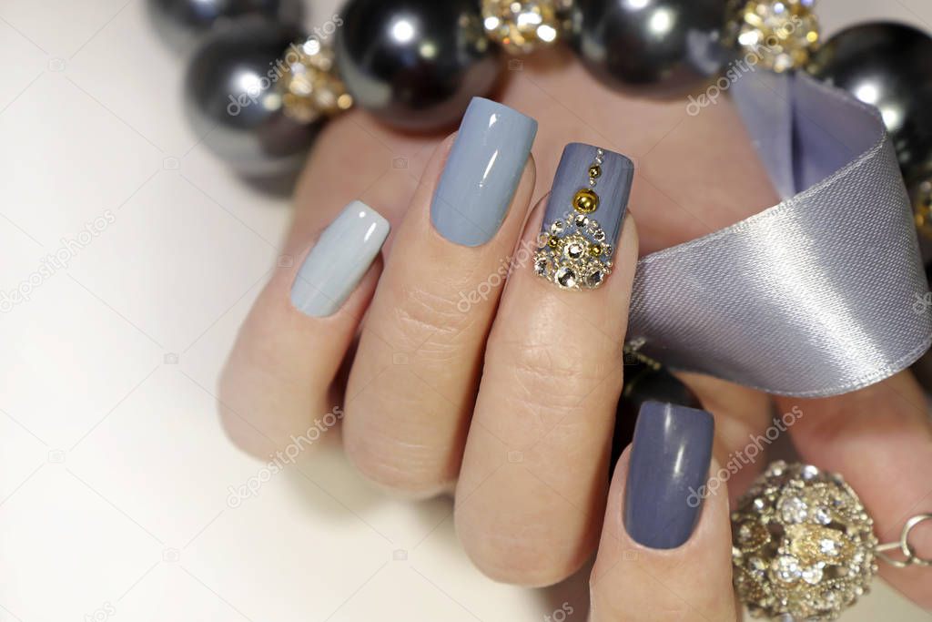 Fashionable grey blue manicure on square shaped nails.Nail art with rhinestones on a light background with decoration.