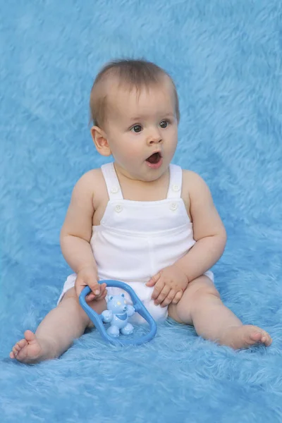 Uma Criança Pequena Senta Fundo Azul Com Brinquedo Suas Mãos — Fotografia de Stock