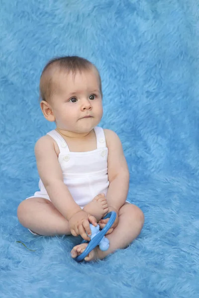 Uma Criança Pequena Senta Fundo Azul Com Brinquedo Suas Mãos — Fotografia de Stock