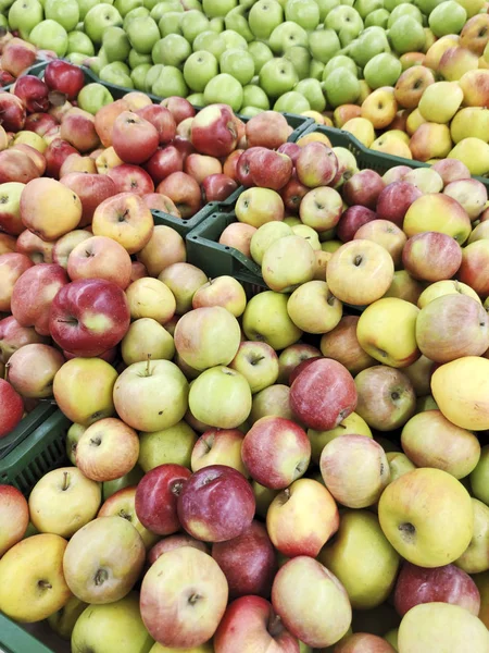 Sale of different varieties of apples in yellow, green, red in large quantities in the store. Fruit background.