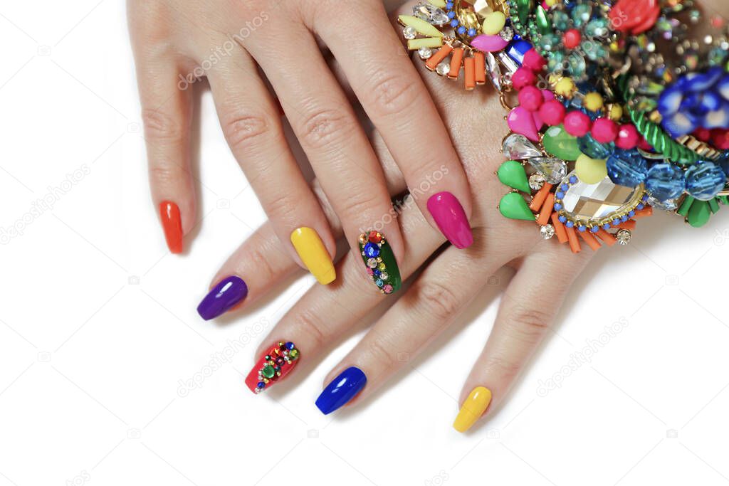 Creative bright saturated manicure on long nails with rhinestones.Nail art on women's hands on a white background with costume jewelry.