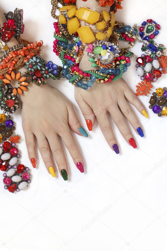 Bright rich multi-colored manicure on long nails with various types of jewelry made of beads and rhinestones.