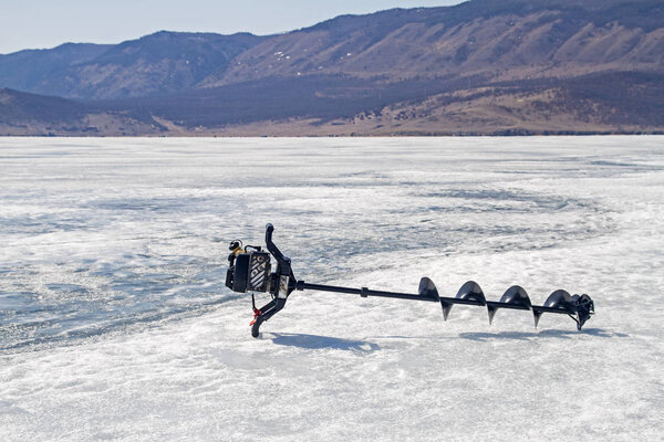 The drilling rig on the ice of Lake Baikal on a mountain background.