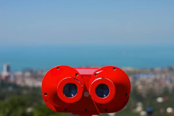 The red coin operated binoculars on the panoramic view of the city Batumi from rooftop platform on the Black Sea with blue sky background. — Stock Photo, Image