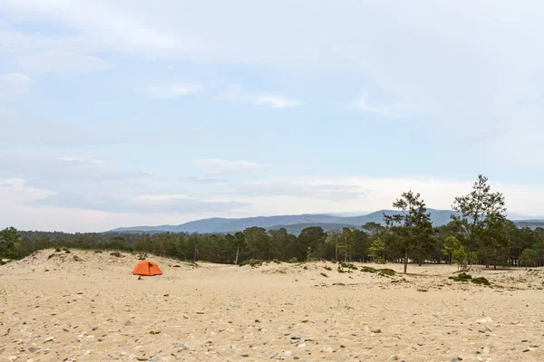 Zelt am Sandstrand am Ufer des Baikalsees im Sommer zwischen Nadelbäumen auf Bergkulisse. — Stockfoto