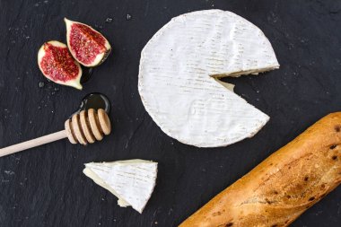 Camembert peyniri ve peynir kafa, bal ve bir kaşık bal ve baget grafit arka plan üzerinde için incir parçaları üçgen iştah açıcı parçası.
