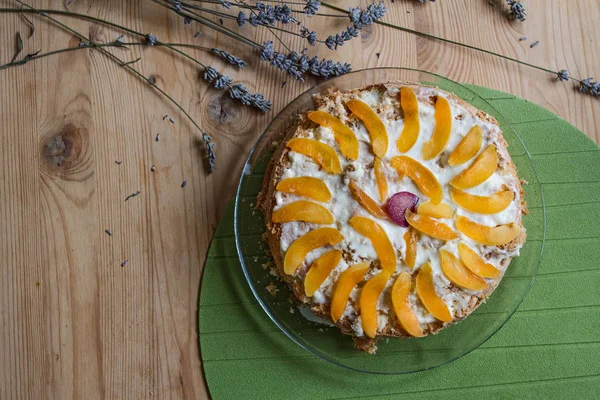 Hausgemachter Kuchen mit Stücken von reifen Pfirsichen und Pflaumen und getrockneten Lavendelblüten auf einem Holztisch. — Stockfoto