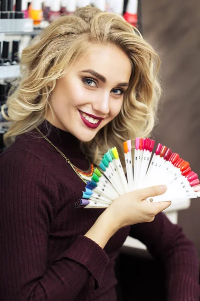 Mulher loira escolhendo a cor de esmalte de unhas — Fotografia de Stock