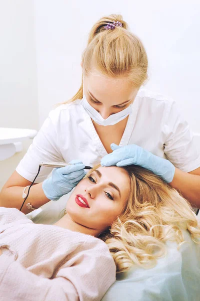 Cosmetologist applying permanent make up on eyebrows Stock Photo