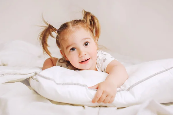 Criança deitada na cama em casa. 2 anos de idade bebê repousa sobre travesseiro branco . — Fotografia de Stock