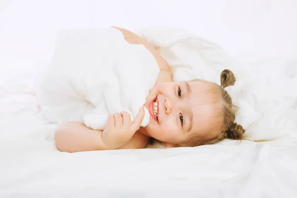 Bambino piccolo sdraiato sul letto a casa. 2 anni bambino poggia su una coperta bianca . — Foto Stock