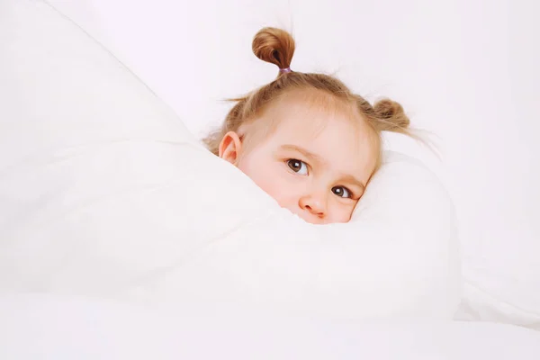 Petit enfant couché sur le lit à la maison. 2 ans bébé repose sur une couverture blanche . — Photo