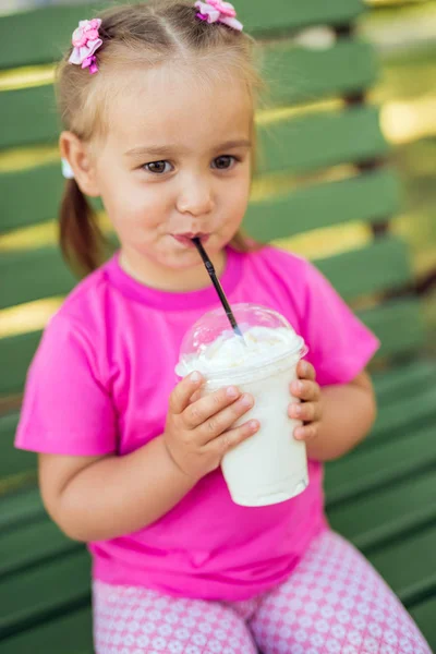 Little girl drinking milkshake through a straw — Stock Photo, Image