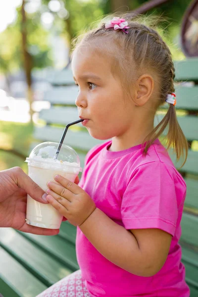 Little girl drinking milkshake through a straw — Stock Photo, Image