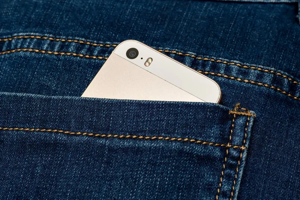 mobile phone in the back pocket of jeans trousers .