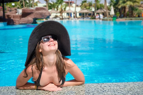 Una donna con un cappello galleggiante in una piscina — Foto Stock