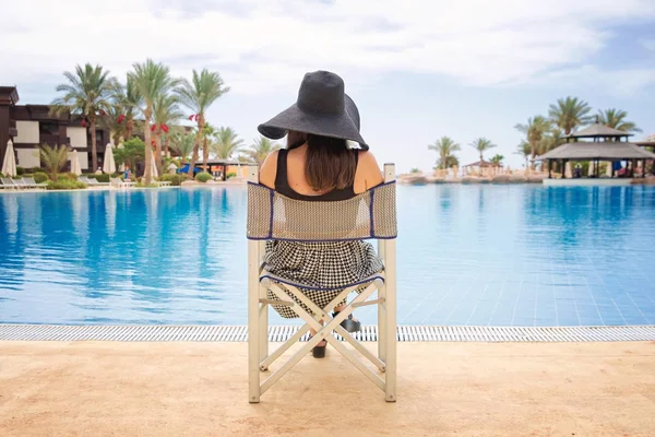 Mulher de chapéu preto perto da piscina — Fotografia de Stock