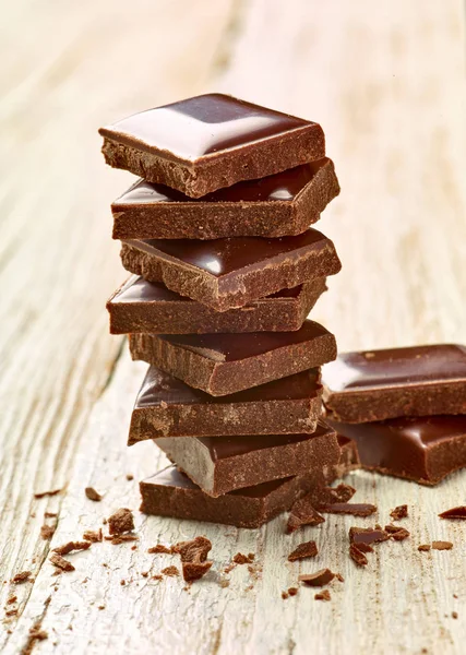 Tahta arka planda çikolata parçalarını kapat