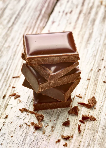 Tahta arka planda çikolata parçalarını kapat