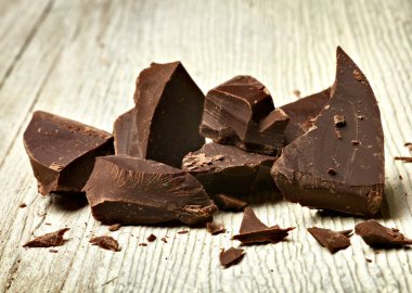 Tahta arka planda çikolata parçalarını kapat